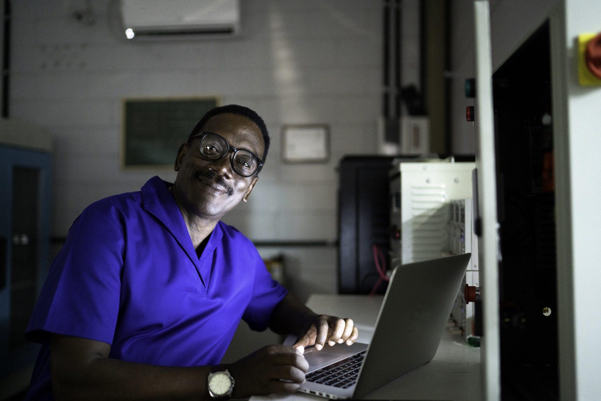 Portrait of man working late and using laptop in industry